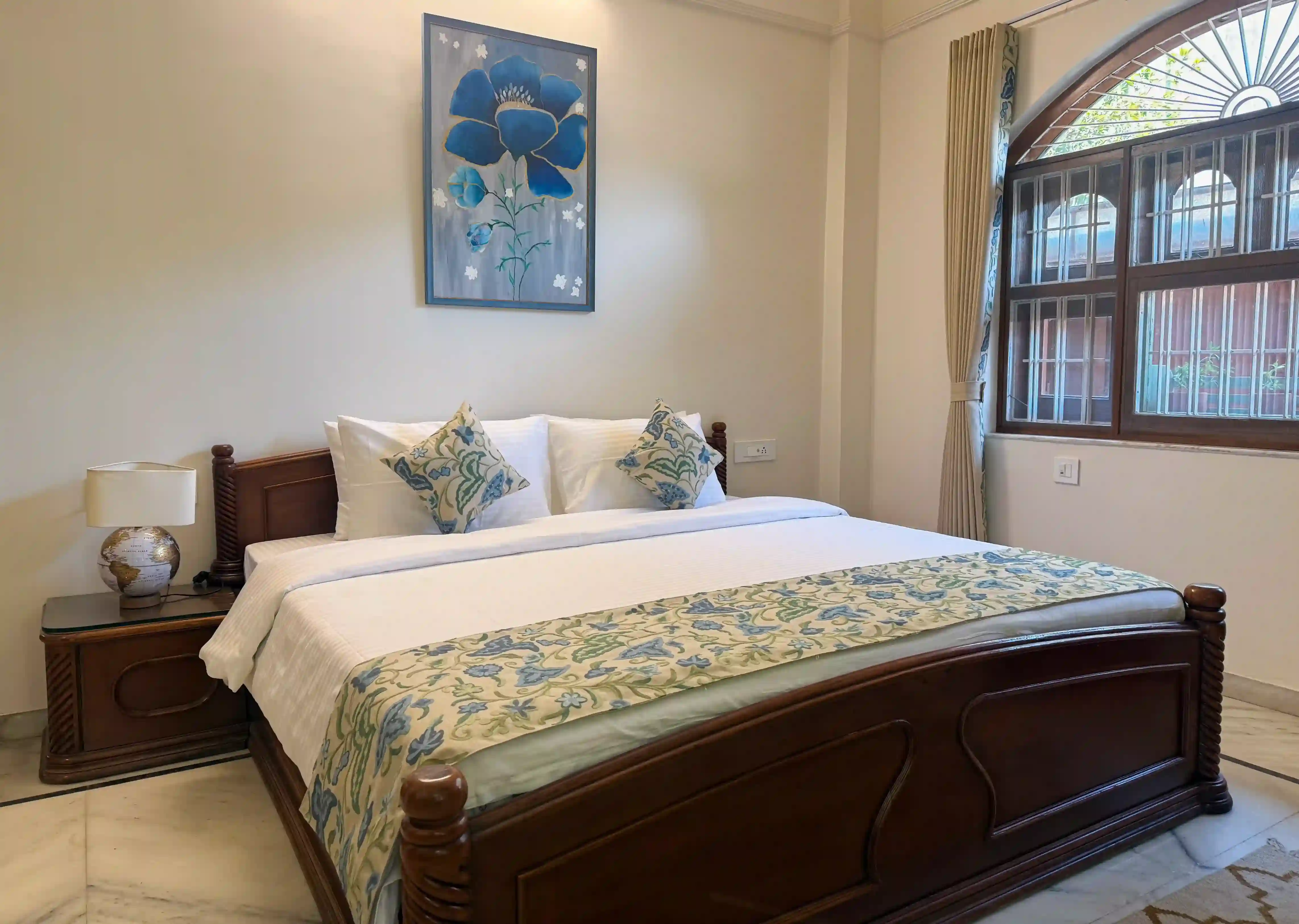 Gulmohar, a ground-floor suite at ArtRest Ahmedabad with a carved wood bed and original floral artwork.